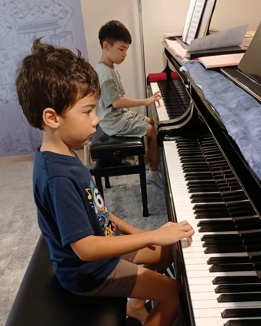 Two young students playing piano together
